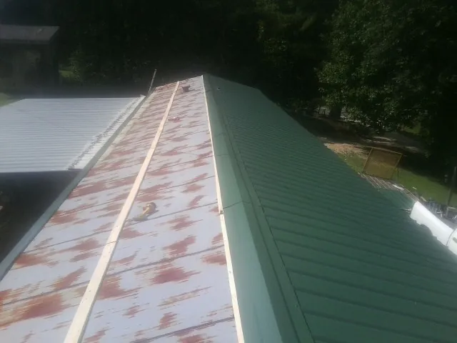 Old rusted panels beside newly installed green metal roofing — Wind Damage Roof Repair by Roofing Brothers in Mount Arlington