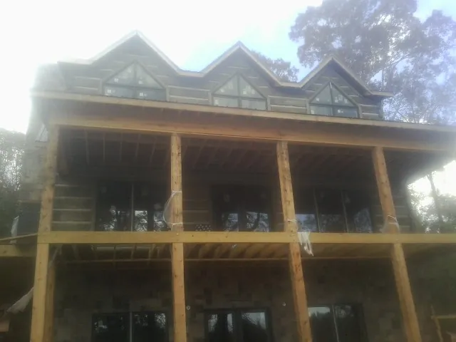 Dormers and porch framing on a large log home under construction — Roof Coating work by our crew in Mount Arlington