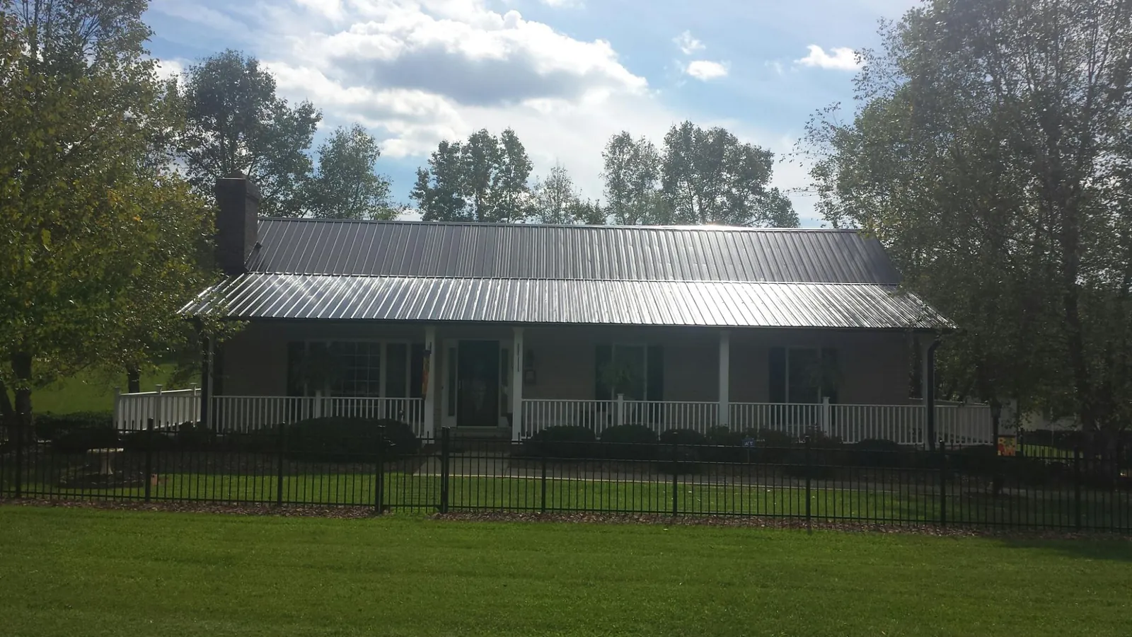 Gray metal roof on a brick ranch with a full width front porch — Gutter Guard Installation work by our crew in Mount Arlington