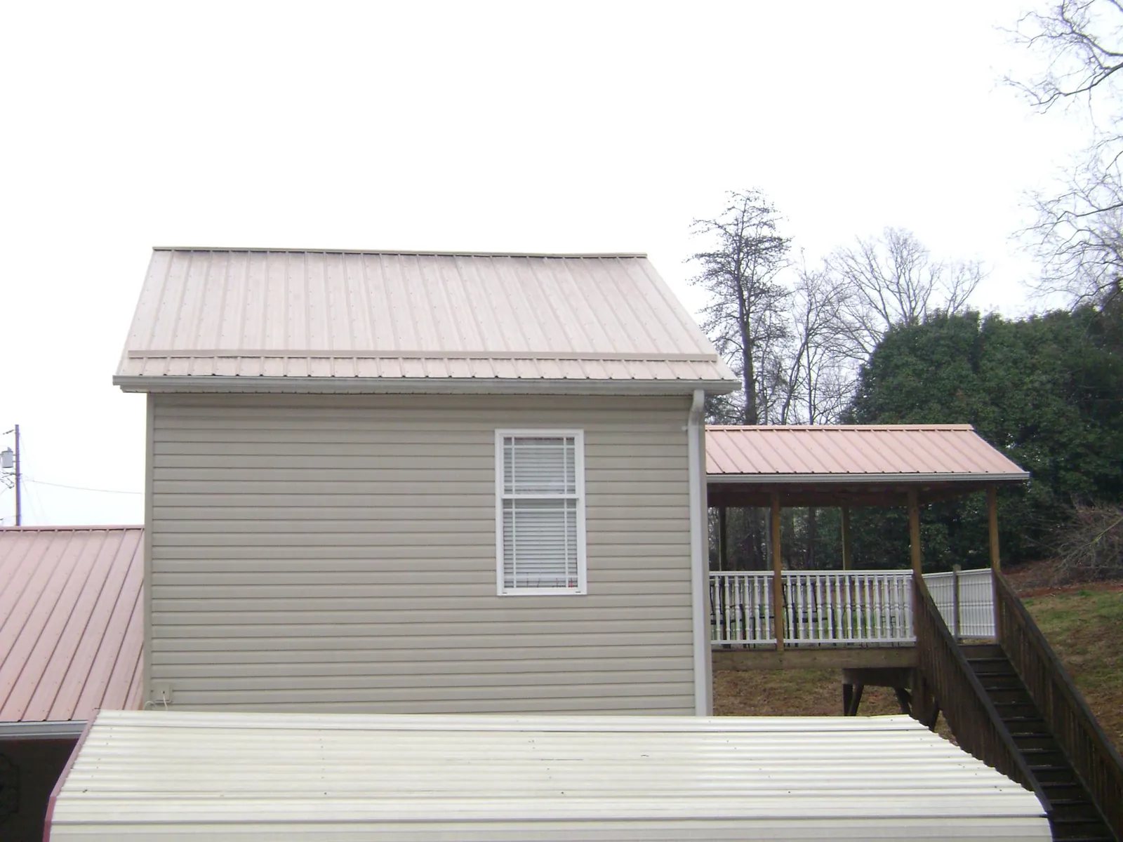 Tan metal roofs on a two story addition and attached porch, from a Roof Replacement job in Mount Arlington
