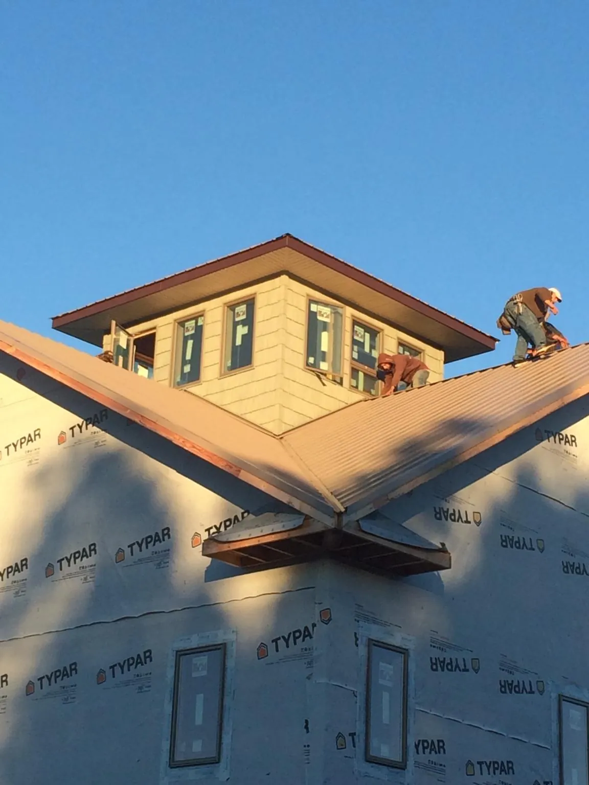 Roofers working around a rooftop cupola on a new metal roof at sunset — Roof Waterproofing in Mount Arlington by Roofing Brothers